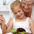 Happy grandmother cooking a salad with granddaughter